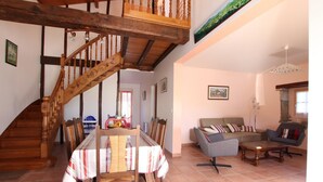 A dining area with a wooden staircase, a dining table with chairs, a sofa, and a lamp. - Ur-ondoa - Larceveau (LARCEVEAU)