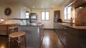 A modern kitchen with a central island, stainless steel appliances, and a marble backsplash. - Airosa - Sare - Gîte (SARE)