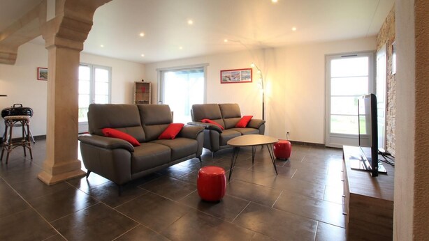 A spacious living room with two sofas, a coffee table, and a red ottoman. - Airosa - Sare - Gîte (SARE)