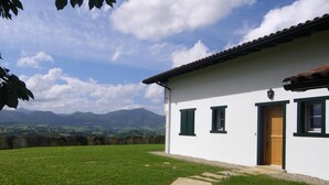 A white building with green shutters, a stone pathway, and a mountainous backdrop. - Airosa - Sare - Gîte (SARE)