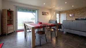 A modern kitchen with a dining area, featuring a wooden table, chairs, and a grey sofa. - Airosa - Sare - Gîte (SARE)