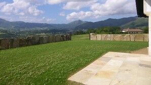 A stone wall with a grassy area and a stone patio. - Airosa - Sare - Gîte (SARE)