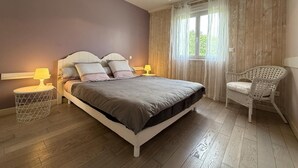 Une chambre à coucher avec un lit, des lampes de chevet, une chaise et une fenêtre avec des rideaux.
