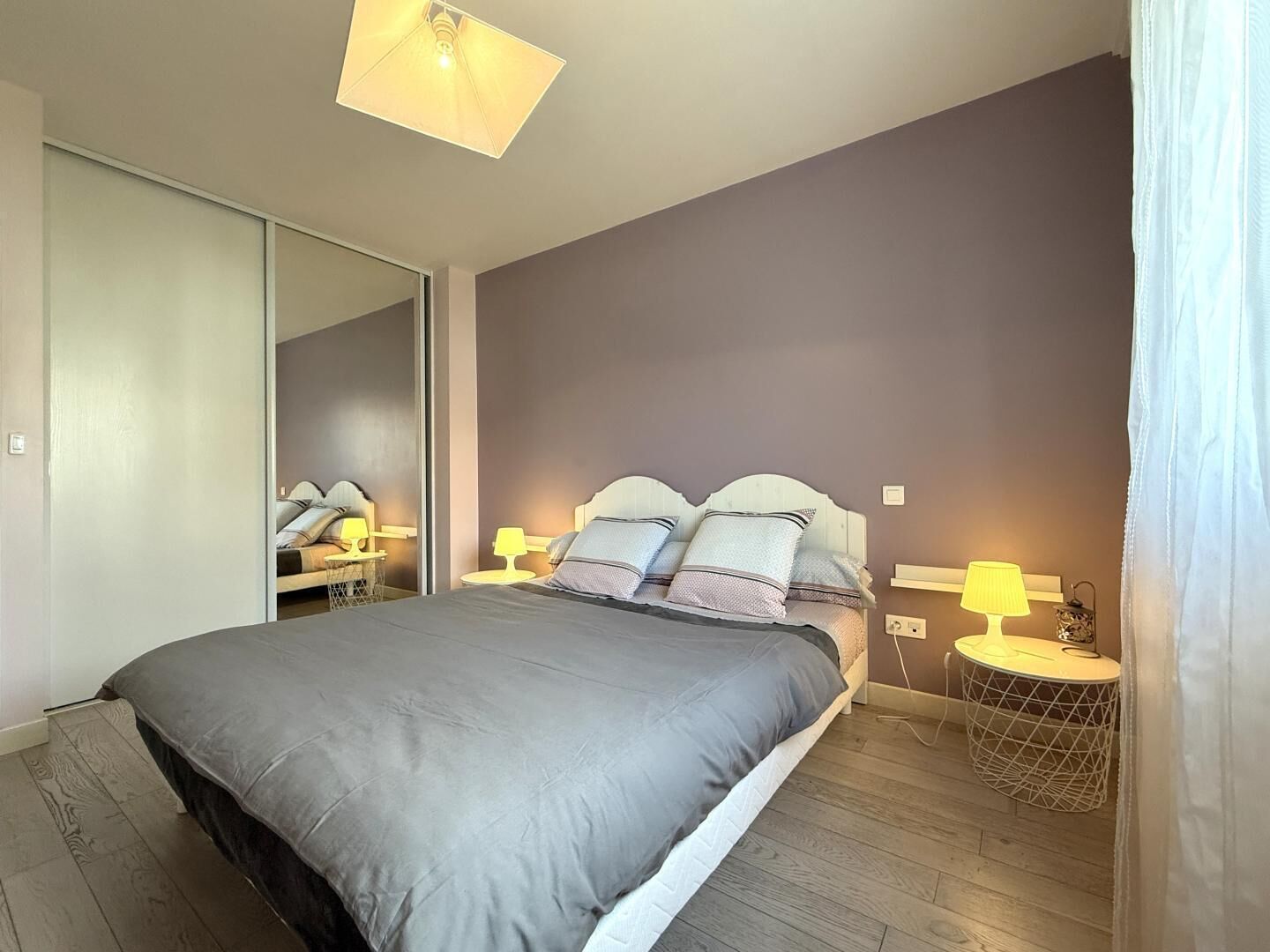 Una camera da letto con un letto, comodini, lampade, uno specchio e un armadio.