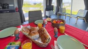 Desayuno con pan, huevos y zumo de naranja sobre un mantel rojo.