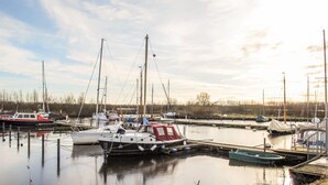 Una marina con varios barcos amarrados, agua tranquila y cielo despejado.