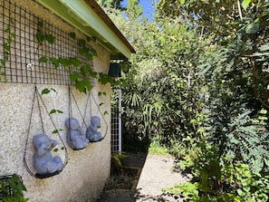A building with a textured wall, a metal grid, and a swing hanging from the wall. - Cauhape - Auga - Gîte (AUGA)