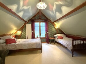 A bedroom with two beds, a window with curtains, a small table, and a hanging light fixture. - Cauhape - Auga - Gîte (AUGA)