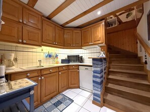 A kitchen with wooden cabinets, a dishwasher, and a microwave. - Cauhape - Auga - Gîte (AUGA)