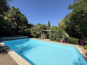 A clear blue swimming pool surrounded by lush greenery and a pergola structure. - Cauhape - Auga - Gîte (AUGA)