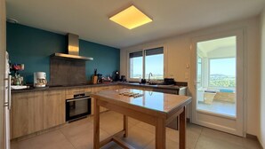 Una cocina moderna con una isla central, horno empotrado y un amplio ventanal con vistas.
