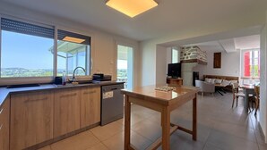 Una cocina moderna con lavavajillas, encimera de madera y un amplio ventanal con vistas al exterior.