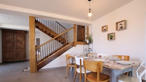 Un comedor con una escalera de madera, una mesa de comedor lista para seis personas y una lámpara colgante.