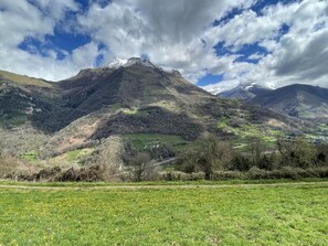 A mountainous landscape with a clear sky and patches of green fields.
