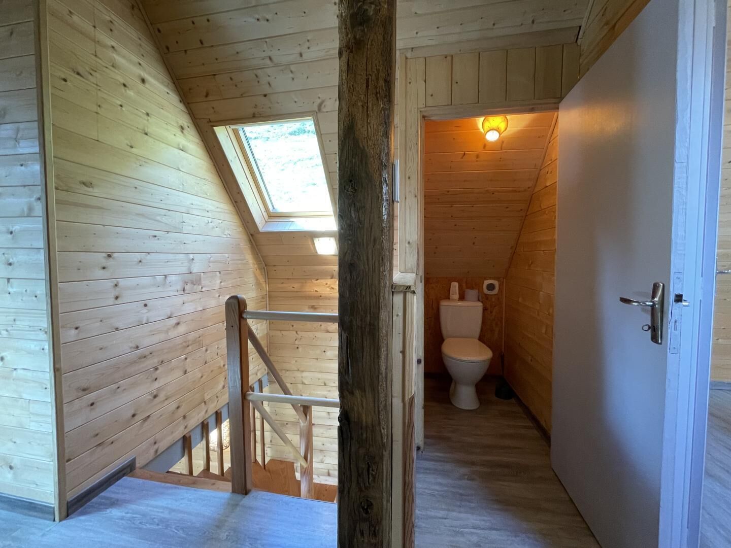 Een houten interieur met dakraam, een kleine badkamer en een houten deur.