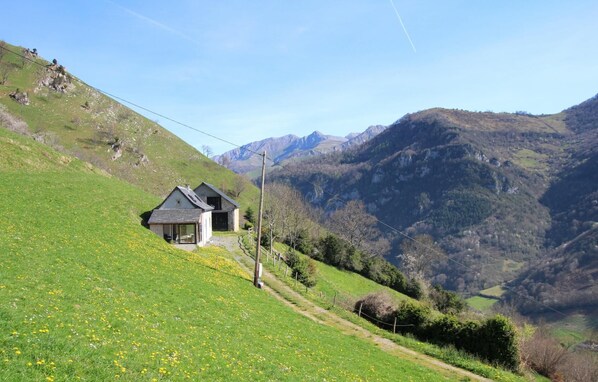 A house on a hillside with a view of mountains.
