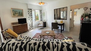 A living room with a sofa, a television, a dining table, and a chair.