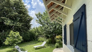 A patio with two lounge chairs, a stone pathway, and a wooden pergola.