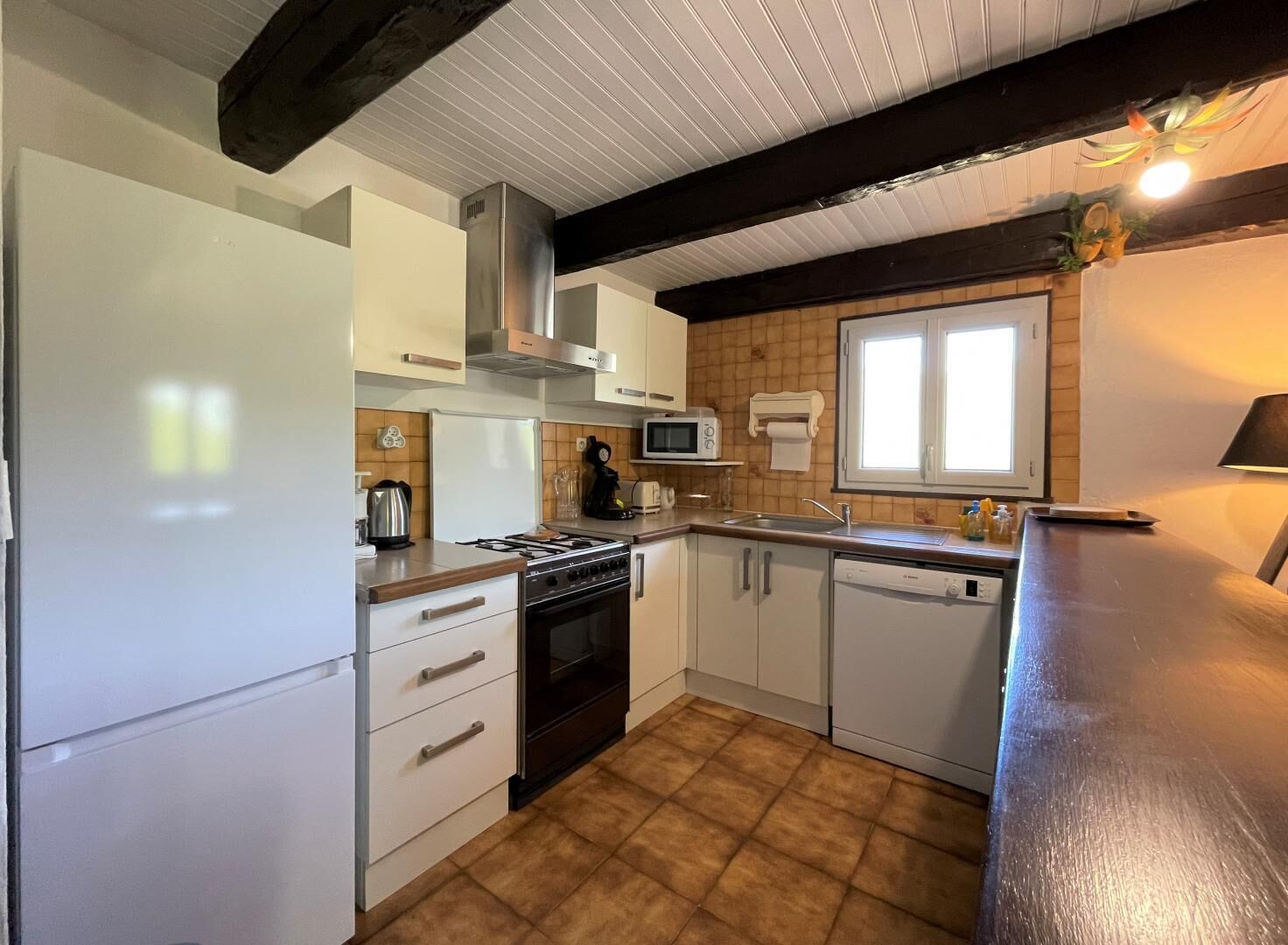 A compact kitchen with white cabinets, a stove, microwave, and a dishwasher.