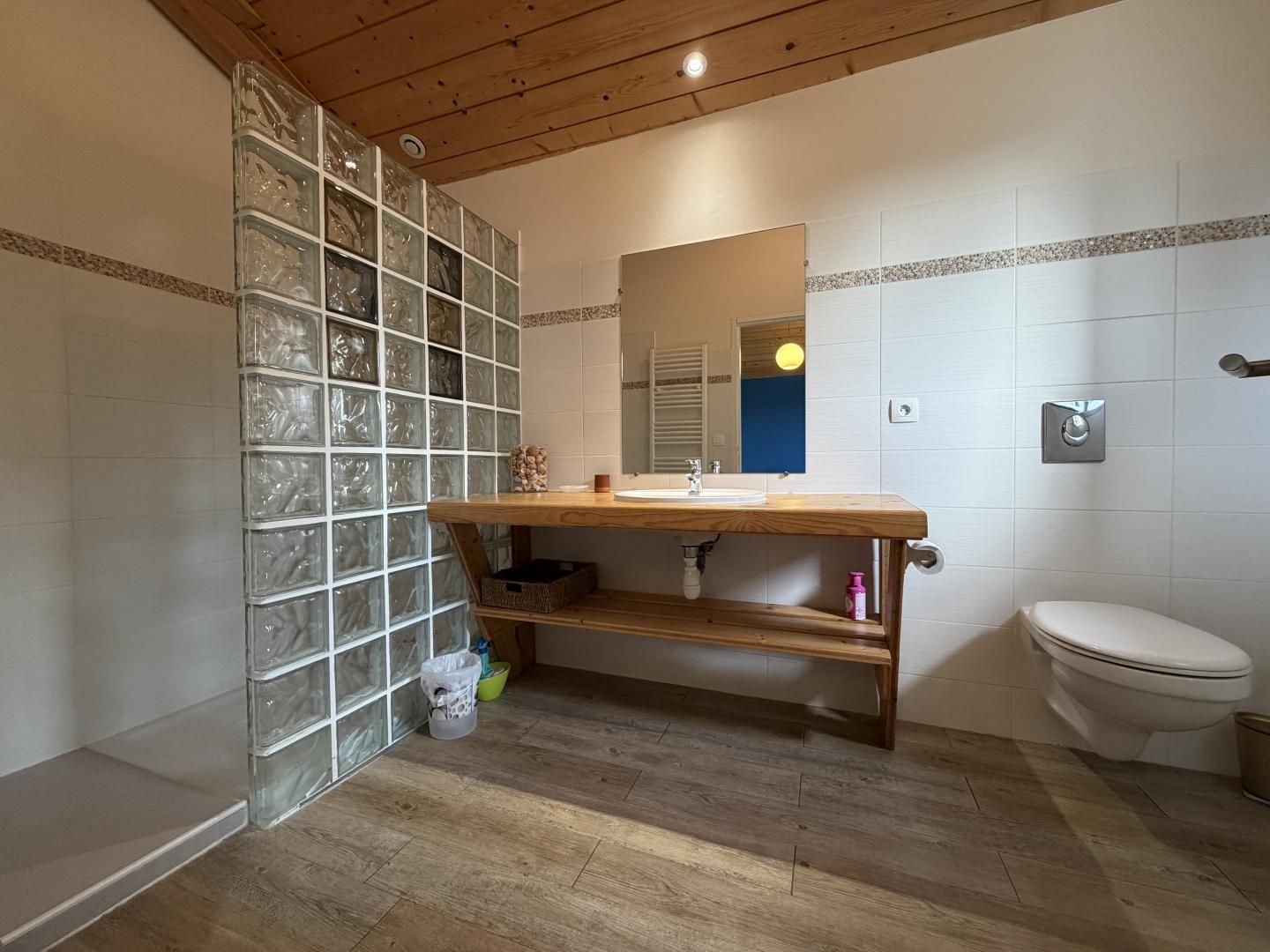A bathroom with a wooden vanity, a glass shower enclosure, and a white toilet.