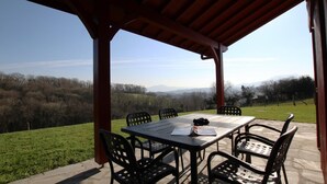Un patio al aire libre con una mesa y sillas, con vistas a un paisaje pintoresco.