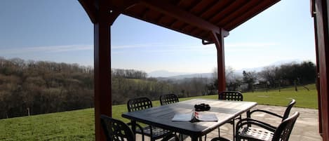 An outdoor patio with a table and chairs, overlooking a scenic landscape.