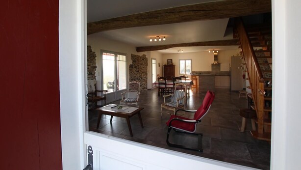 Amplia sala de estar con pared de piedra, una mesa de comedor y varias sillas.