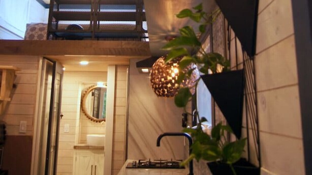 A modern kitchen with wooden ceiling beams, a black hanging light fixture, and a black metal wall-mounted light.