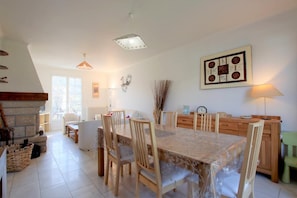 A spacious dining area with a large table and chairs, a fireplace, and a view of the outdoors. - Geriza - Uhart-cize - Gîte (UHART-CIZE)