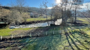 Paesaggio rurale con un fiume, una casa bianca e un recinto di legno.