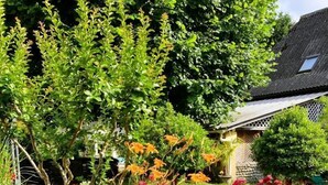 A garden with various plants and flowers, a stone pathway, and a house in the background. - CHEZ CASTAGNET - ASSAT (ASSAT)
