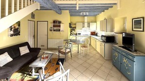 A spacious living area with a sofa, coffee table, and chairs, a kitchen with a dining table, and a balcony with a railing. - CHEZ CASTAGNET - ASSAT (ASSAT)