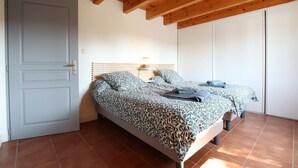 Un dormitorio con cama, mesita de noche, lámpara y puerta.