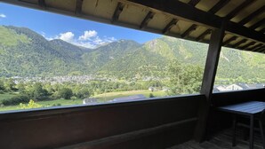 Une terrasse en bois offrant une vue sur une vallée et des montagnes.