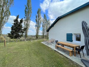 Relax in a serene outdoor space with a picnic table and chairs, surrounded by a beautifully maintained lawn and a large tree.