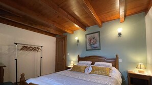 A bedroom with a wooden bed, a wooden ceiling, a wall-mounted lamp, and a door. - Larzabalea - Sare - Gîte (SARE)