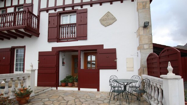 A traditional building with a stone patio, a balcony, and a table with chairs. - Larzabalea - Sare - Gîte (SARE)