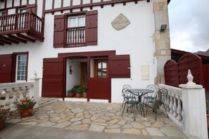 A traditional building with a stone patio, a balcony, and a table with chairs. - Larzabalea - Sare - Gîte (SARE)