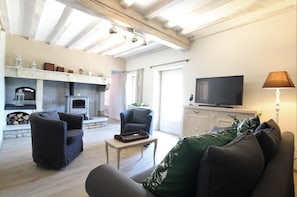 Uma sala de estar com lareira, televisão e sofá.