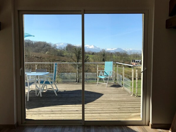 A wooden deck with a table and chairs, a glass door leading to a scenic view of mountains and trees. - Millepertuis - Montaut (MONTAUT)