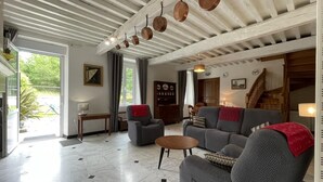 A spacious living room with a high ceiling, a fireplace, and a view of the outdoors. - Domaine Pedelaborde - Poey-d'oloron (POEY-D'OLORON)
