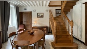 A dining area with a wooden table and chairs, a staircase, and a view of the outside. - Domaine Pedelaborde - Poey-d'oloron (POEY-D'OLORON)