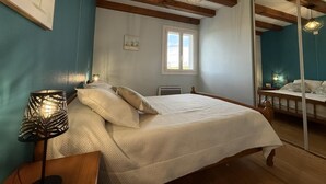 A bedroom with a bed, a nightstand, a lamp, a window, and a mirror. - Aguerrea - Macaye - Gîte (MACAYE)