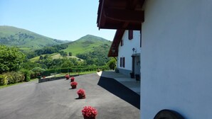 A building with a white facade and a red roof, a paved driveway, and red flower pots. - Aguerrea - Macaye - Gîte (MACAYE)
