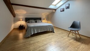 A bedroom with a bed, a chair, a skylight, and wooden beams. - Xearbaita - Urrugne - Gîte (URRUGNE)