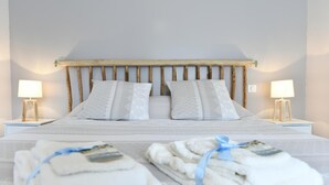 Een net opgemaakt bed met twee kussens, een houten hoofdbord en twee bedlampjes.