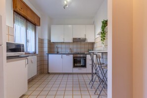 A compact kitchen with white cabinets, a built-in oven, and a microwave.