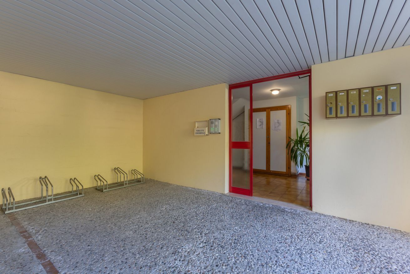 Ein Flur mit einer roten Tür, einer Pflanze und einem an der Wand montierten Briefkasten.
