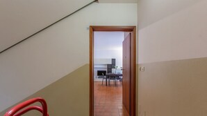 A staircase leading to a dining area with a tiled floor and a view of a kitchen in the background. - GuestHost - Pontelagoscuro Huge & Residential Apartment (Ferrara)