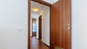 A hallway with a wooden door, a vent, and a light switch on the wall. - GuestHost - Pontelagoscuro Huge & Residential Apartment (Ferrara)